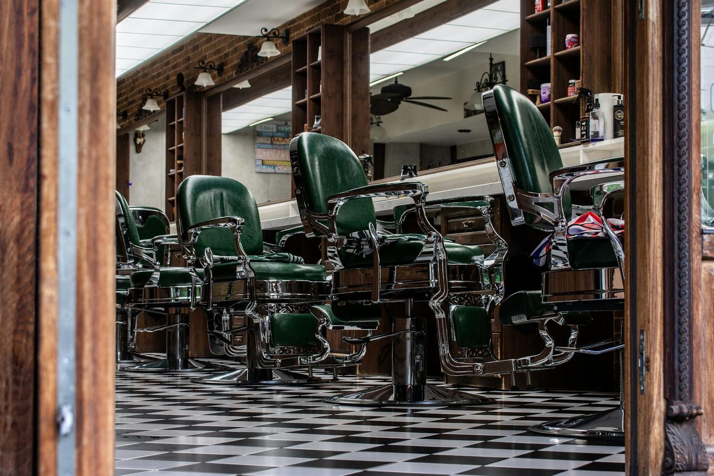 Rangée de fauteuils de barbier vintage en cuir alignés le long du miroir du salon Le Cran